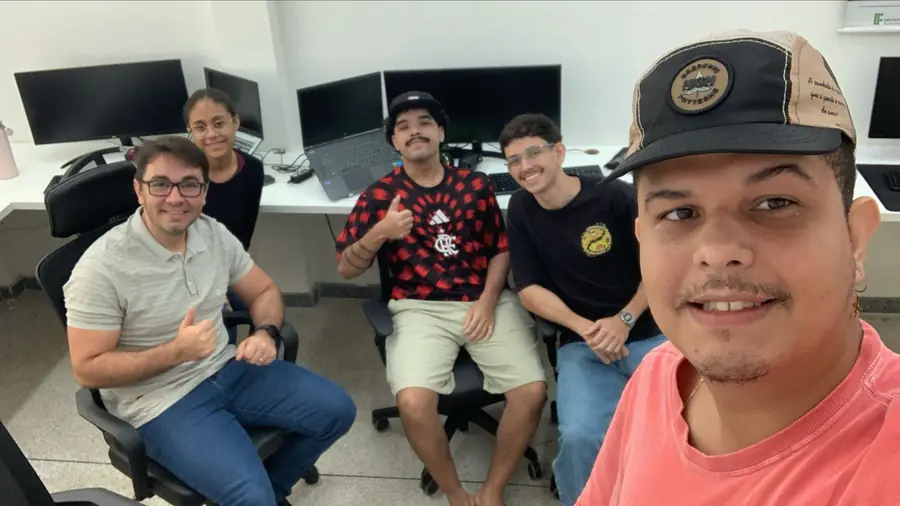 Cinco integrantes do LEDS sentados diante da bancada de monitores do laboratório