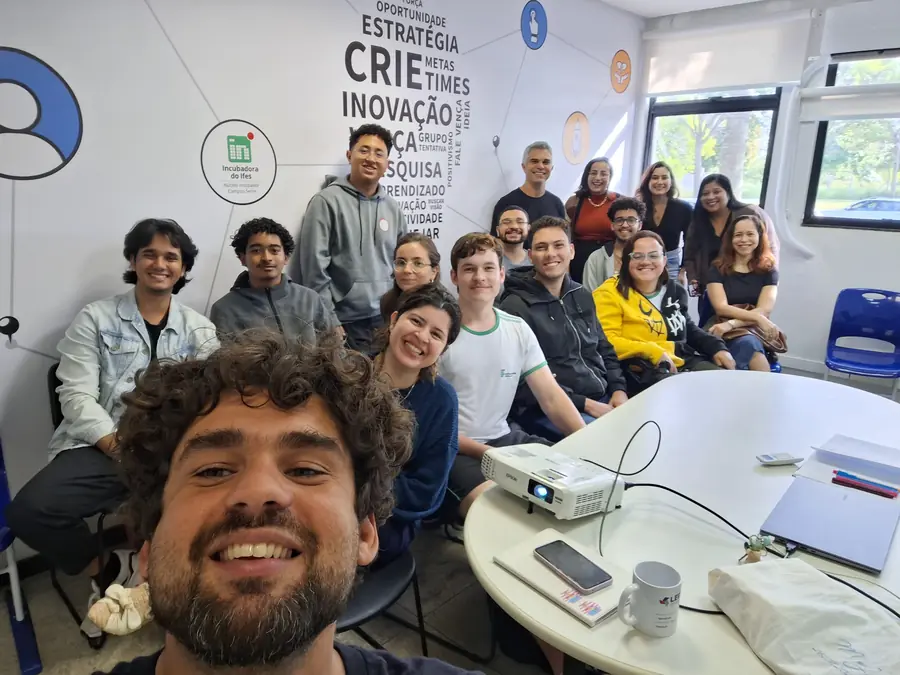 Grupo reunido na sala da Incubadora do Ifes, com nuvem de palavras na parede