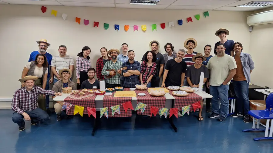 Equipe do LEDS de chapéu de palha atrás da mesa decorada com bandeirinhas
