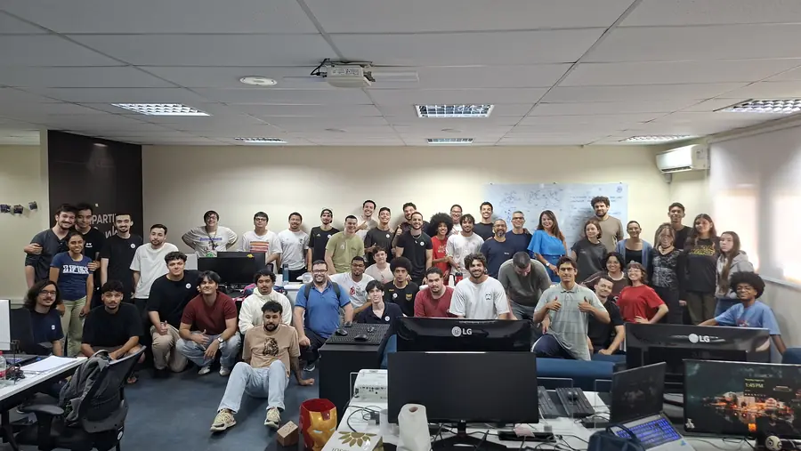 Grupo numeroso posa entre as estações de trabalho do laboratório