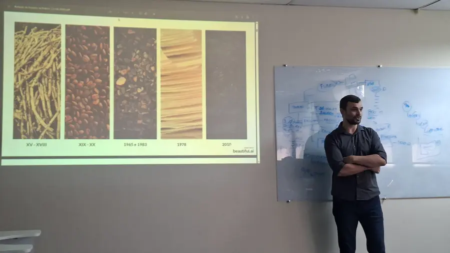 Instrutor ao lado do quadro branco, com slide sobre a evolução dos materiais de escrita